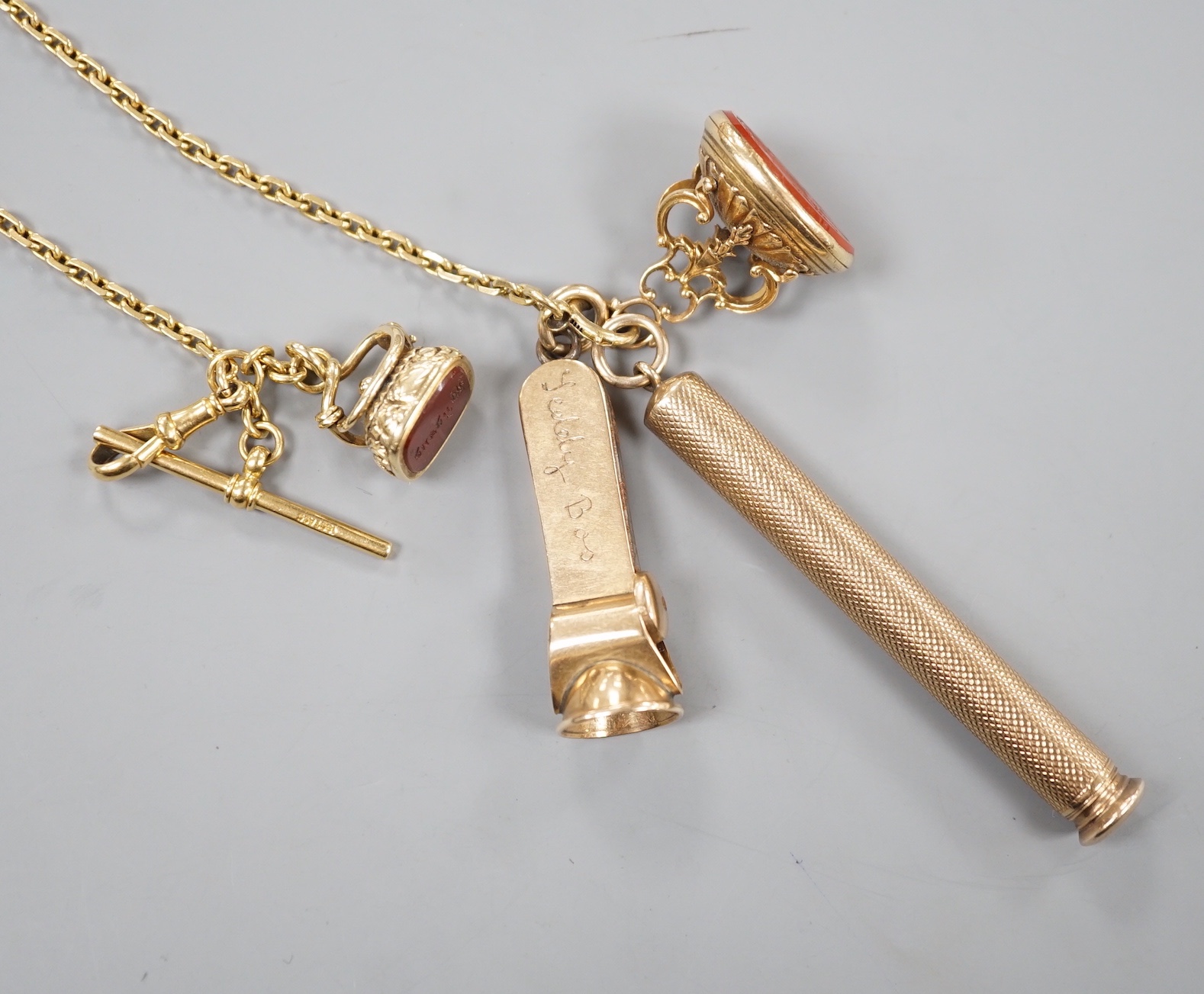 An 18ct albert chain, 33cm, 15 grams, hung with two 19th century yellow metal overlaid and carnelian fob seals, a yellow metal overlaid propelling pencil and a 9ct gold mounted cigar cutter.